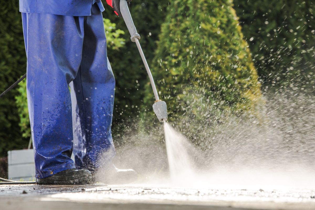 unidentified person using pressure washer to clean a surface