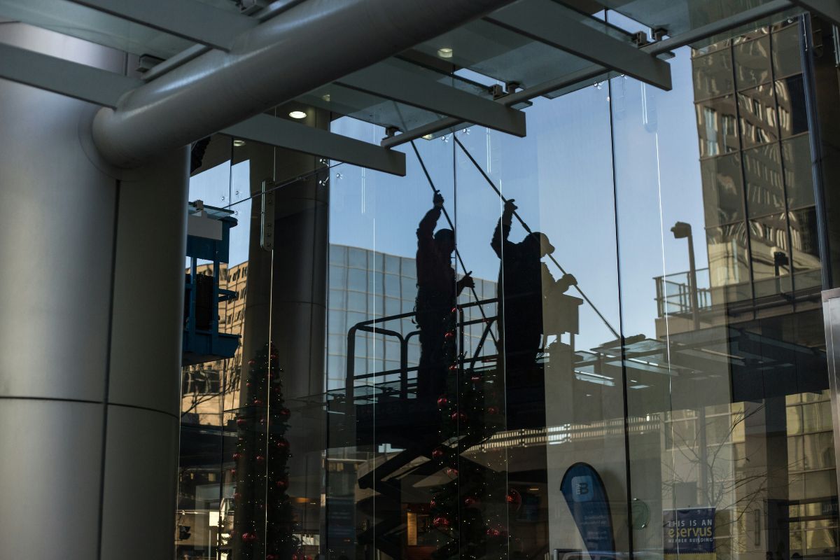 Utility man standing in a platform cleaning glass window