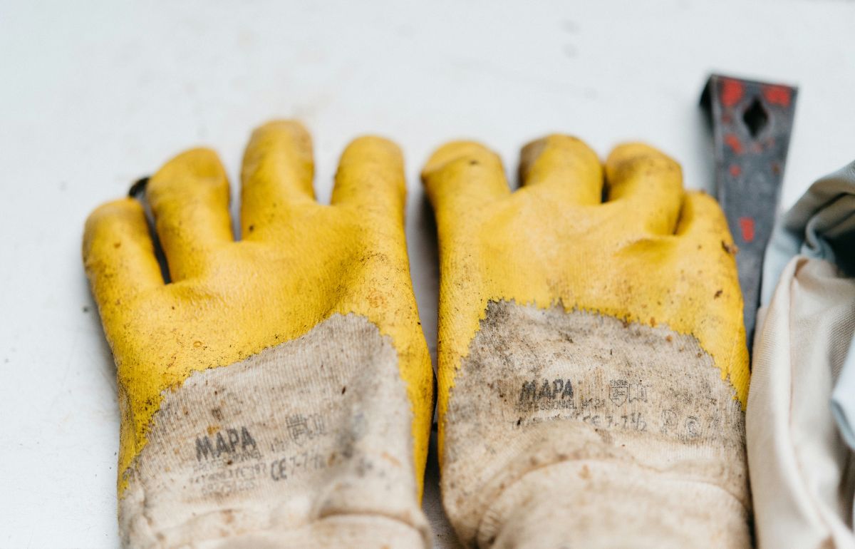 a pair of brown and yellow leather gloves on a light surface